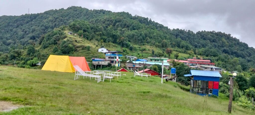 Scenic view of hills with village houses and a tent in the foreground