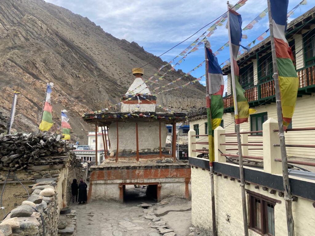 Scenic view of Kagbeni village, the gateway to the Upper Mustang Trek Itinerary, with a large Buddhist stupa, prayer flags, and traditional houses.