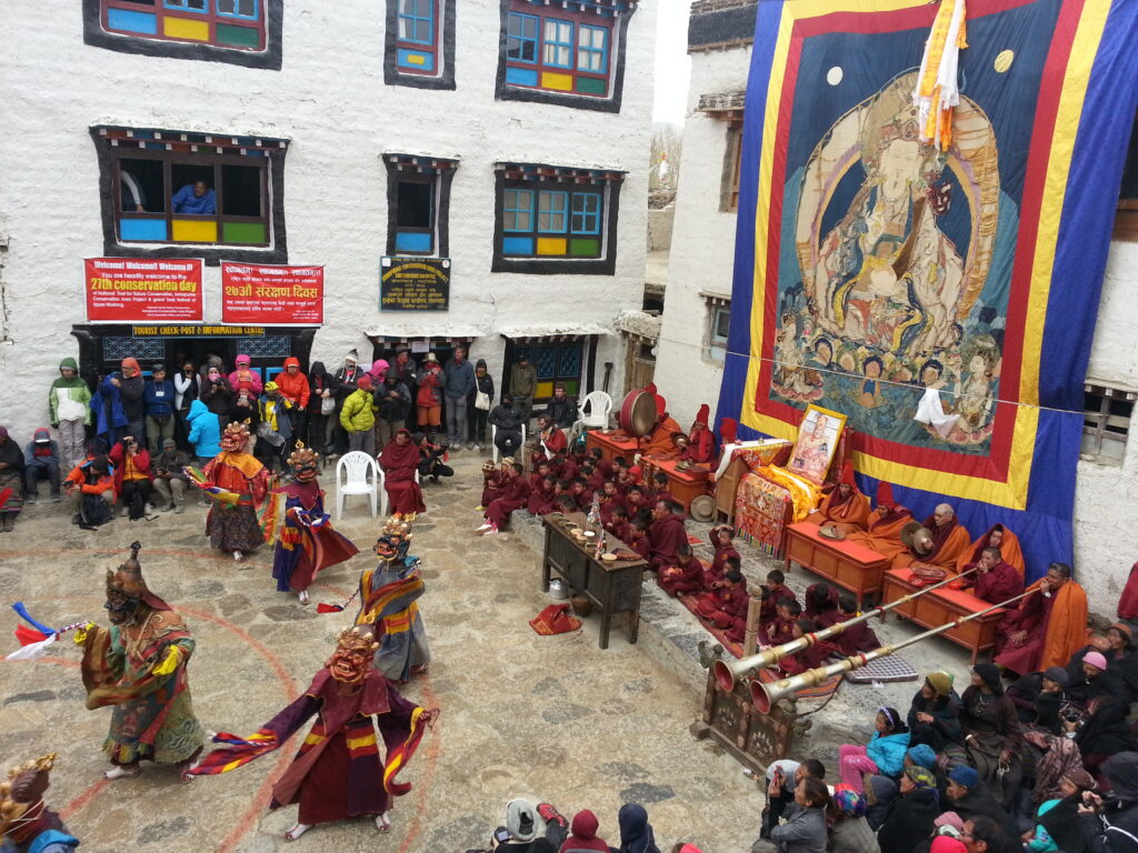 Monks performing traditional Lama dance during the Teji Festival in Lo Manthang, Upper Mustang, with locals watching the colorful performance.