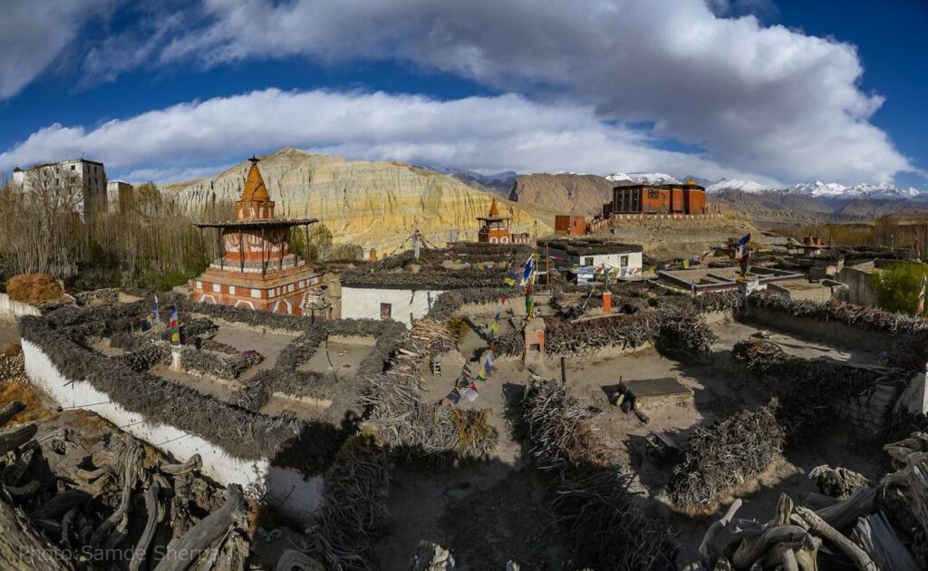 Beautiful view of Tsarang village along the Lo Manthang Trek route in Upper Mustang, with a red Buddhist stupa, monastery, and blue sky.