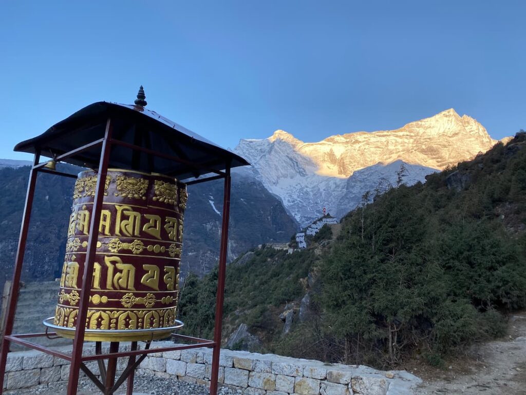 Golden prayer wheel at Namche Bazaar on the Everest Base Camp Trek with snow-capped Himalayan peaks at sunrise