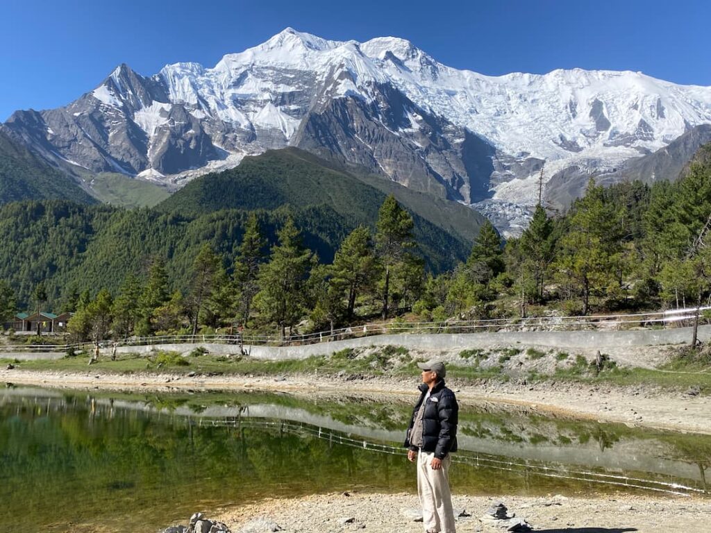 Trekker gazing at Annapurna II from Manang lake on the Annapurna Circuit trekking in Nepal