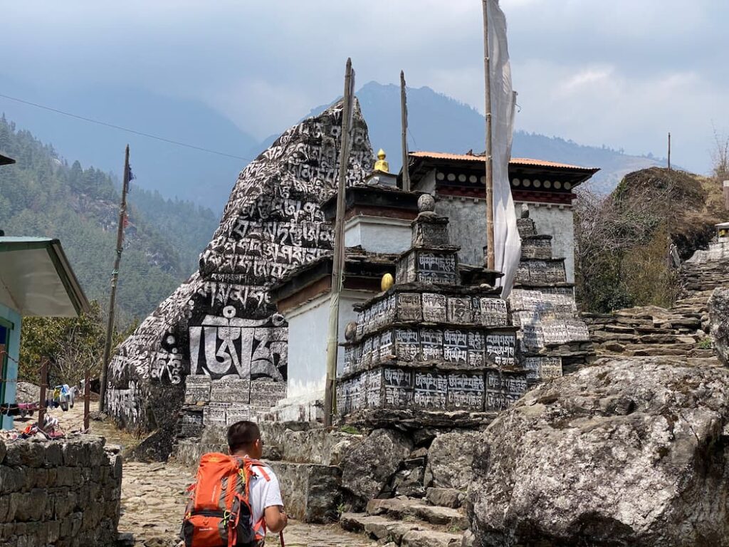 Trekker passing ancient mani wall and chorten in the Everest region Khumbu valley