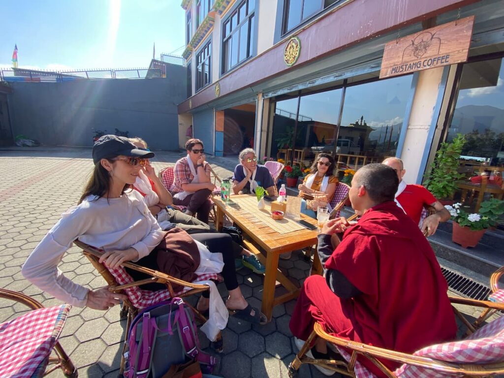 Tour guests enjoying a cultural exchange with a Tibetan Buddhist monk during a cultural tour in Pokhara