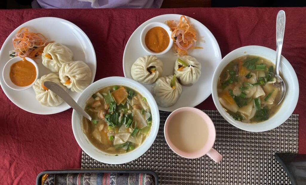 Traditional Tibetan food including steamed momos, thenthuk noodle soup and butter tea