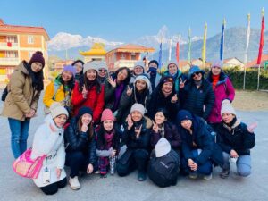 Full day cultural tour in Pokhara – happy group of tourists at the Tibetan settlement with Fishtail mountain and prayer flags behind them