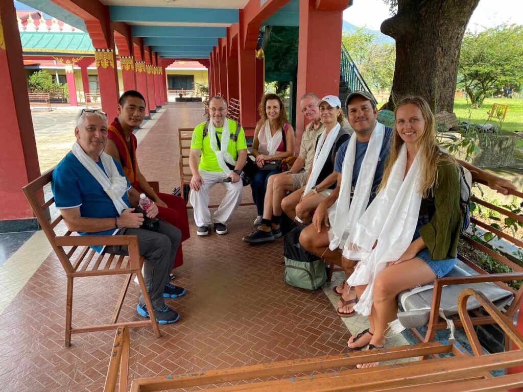 Visitors receiving white khata scarves from a young Buddhist monk inside a monastery