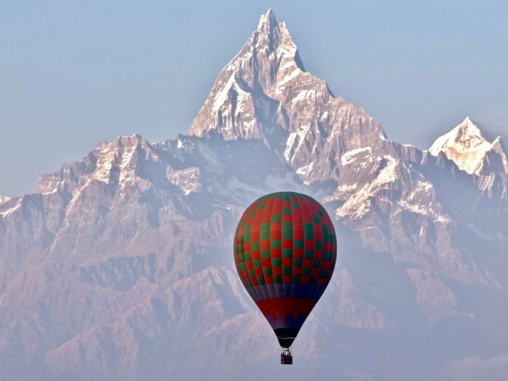 Hot air balloon floating over Pokhara valley with Machhapuchhre (Fishtail Mountain) in the background.