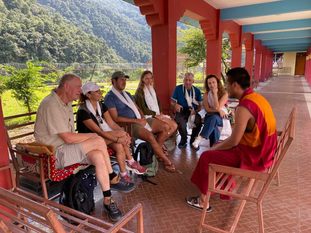 Guests in warm conversation with a young Buddhist monk inside a monastery in Pokhara