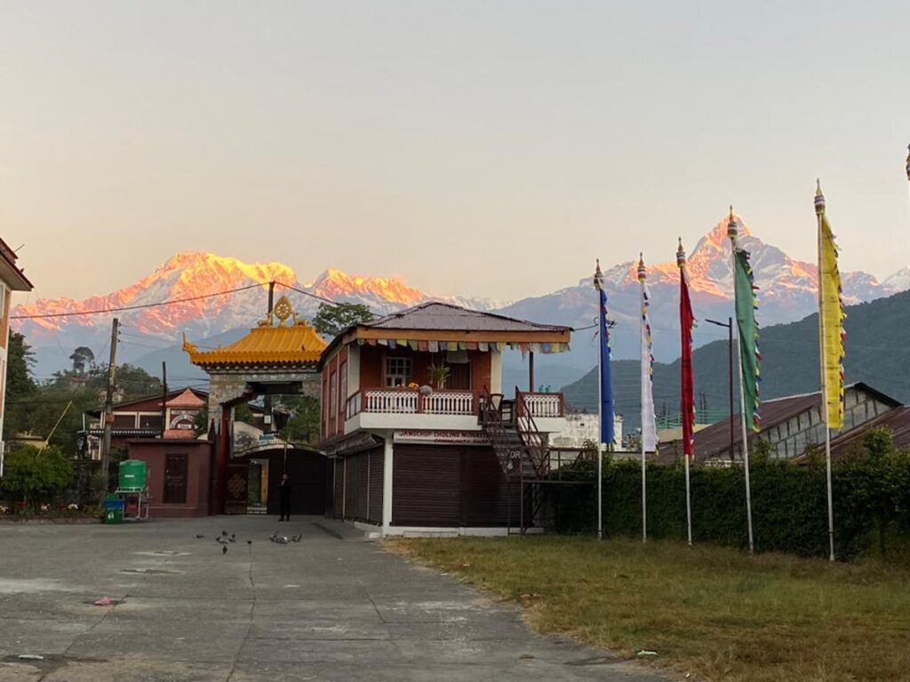 Janschup Choling Monastery at sunset with the Annapurna range glowing orange — a serene scene from the Tibetan cultural tour in Pokhara