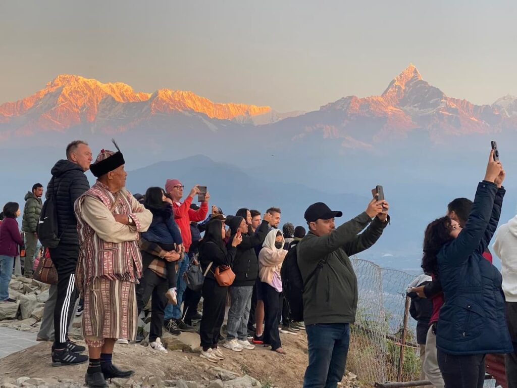 Tourists capturing Annapurna and Machhapuchhre alpenglow at Sarangkot sunrise — best Pokhara sightseeing tour