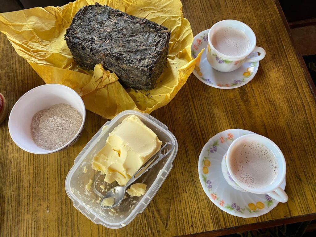 Tibetan afternoon snack during the Pokhara cultural day tour – traditional butter tea, tsampa barley flour, and yak butter at a local family home
