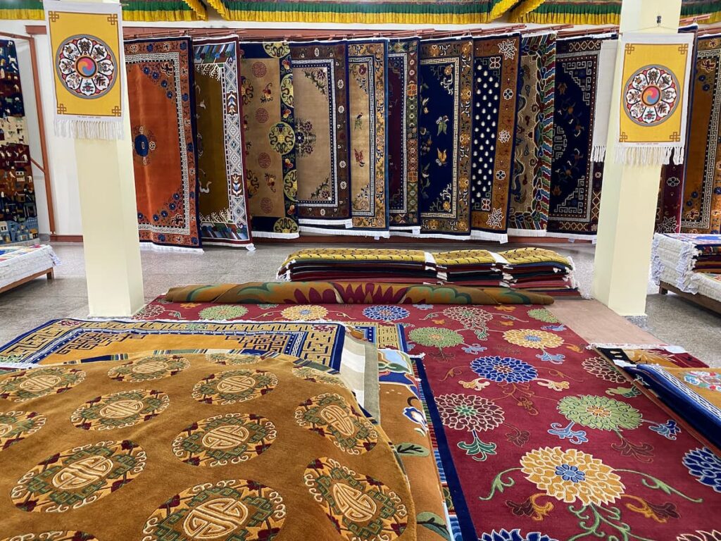Handmade Tibetan carpets with traditional Buddhist patterns displayed in a carpet showroom