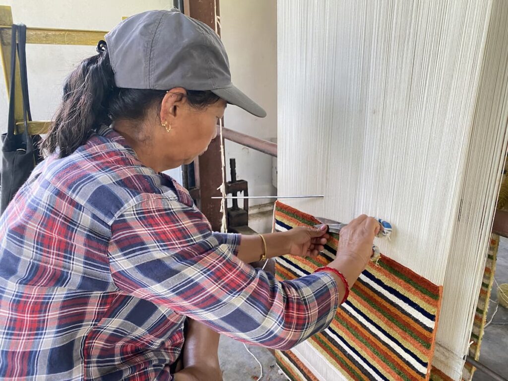Tibetan artisan hand-weaving a carpet at traditional loom — Tibetan culture tour Pokhara