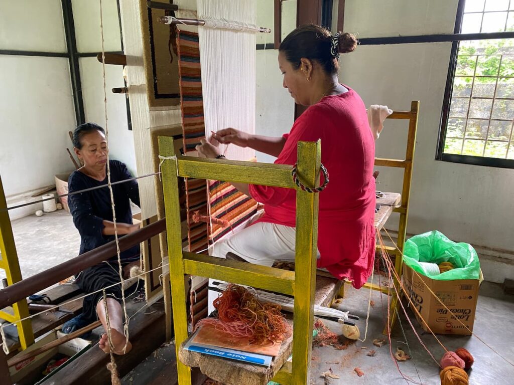 Women handweaving traditional Tibetan carpets on wooden looms at a carpet workshop in Pokhara
