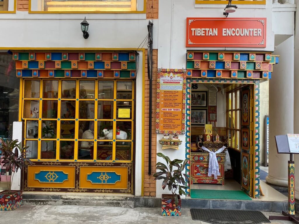 Tibetan Encounter office exterior in Lakeside Pokhara with traditional Tibetan decorative entrance and tour schedule board