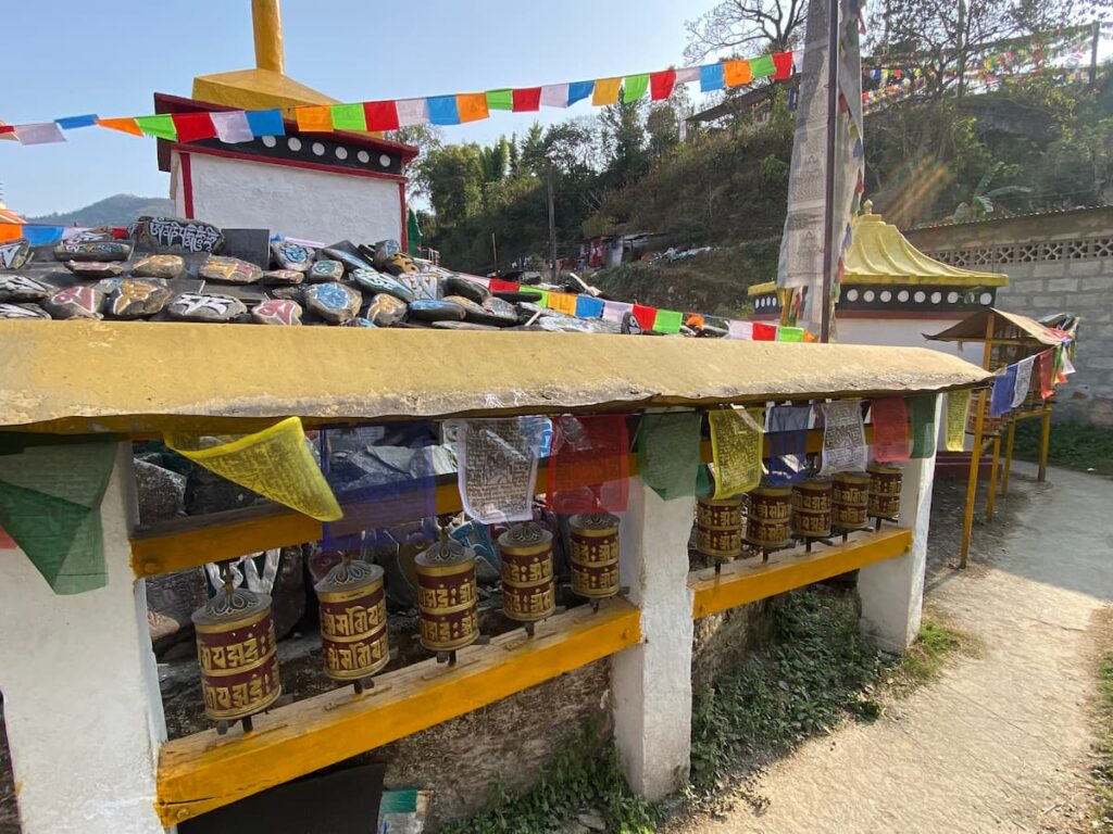 Tibetan monastery tour Pokhara – prayer wheels and mani stones inscribed with Buddhist mantras and colorful prayer flags