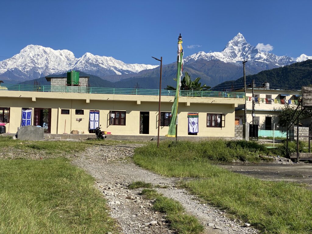Tibetan community residential buildings in Pokhara with prayer flags and snow-capped Machhapuchhre mountain visible in the background