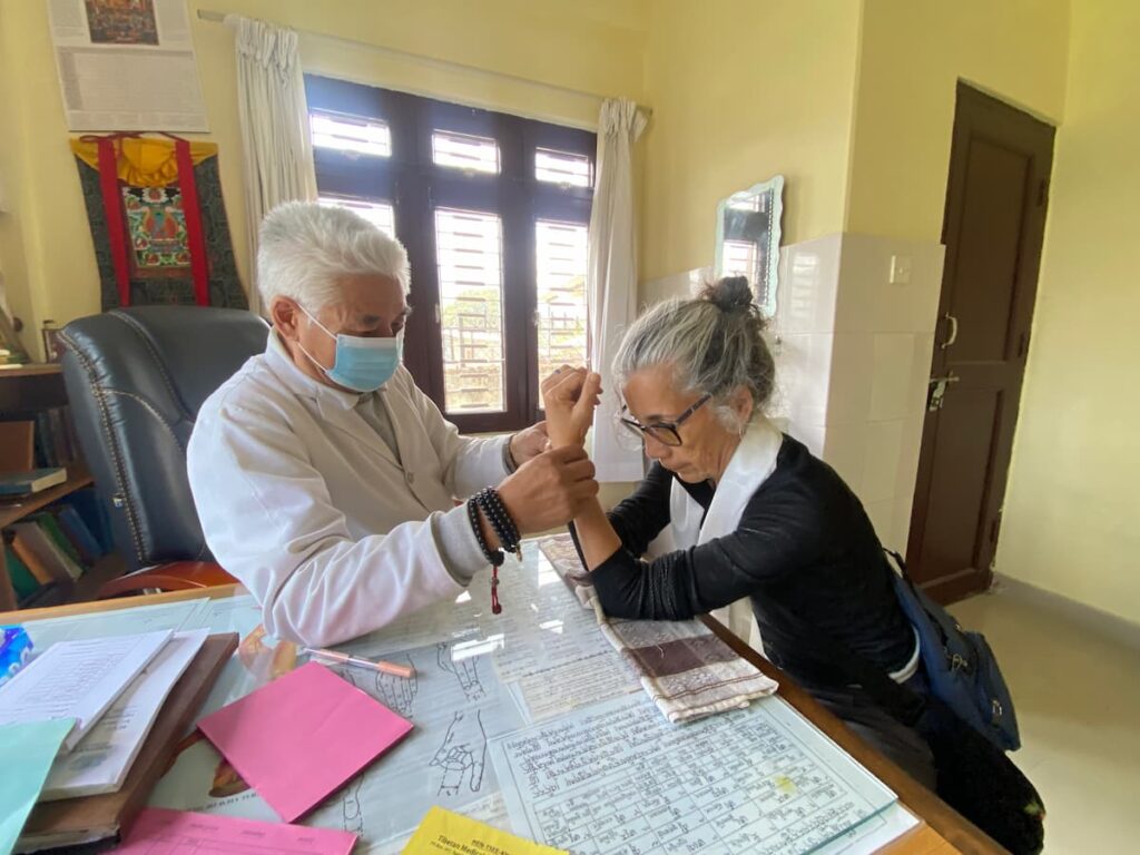Tibetan doctor performing traditional pulse diagnosis on a guest during the cultural tour in Pokhara