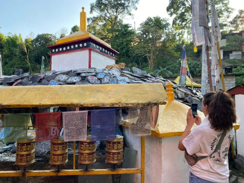 Tourist photographing Tibetan mani stones and prayer wheels at a monastery in Pokhara – things to do in Pokhara morning