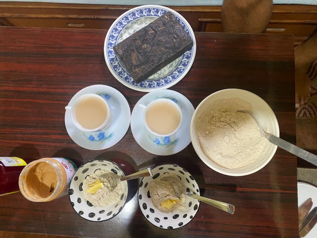 Traditional Tibetan afternoon snacks including butter tea, tsampa roasted barley flour and peanut butter served on a table during the afternoon cultural tour in Pokhara