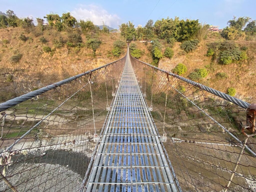 Walking across Bhalam suspension bridge over the river gorge — one of the best places to visit in Pokhara for scenic views.