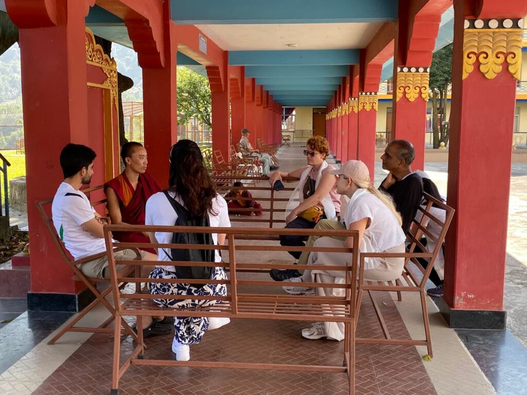 Tour guests having a personal conversation with a young Buddhist monk in the corridor of a Tibetan monastery in Pokhara