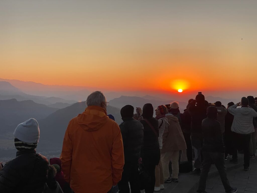 Visitors watching the golden sunrise over the Himalayan mountains from Sarangkot hill during a morning tour in Pokhara