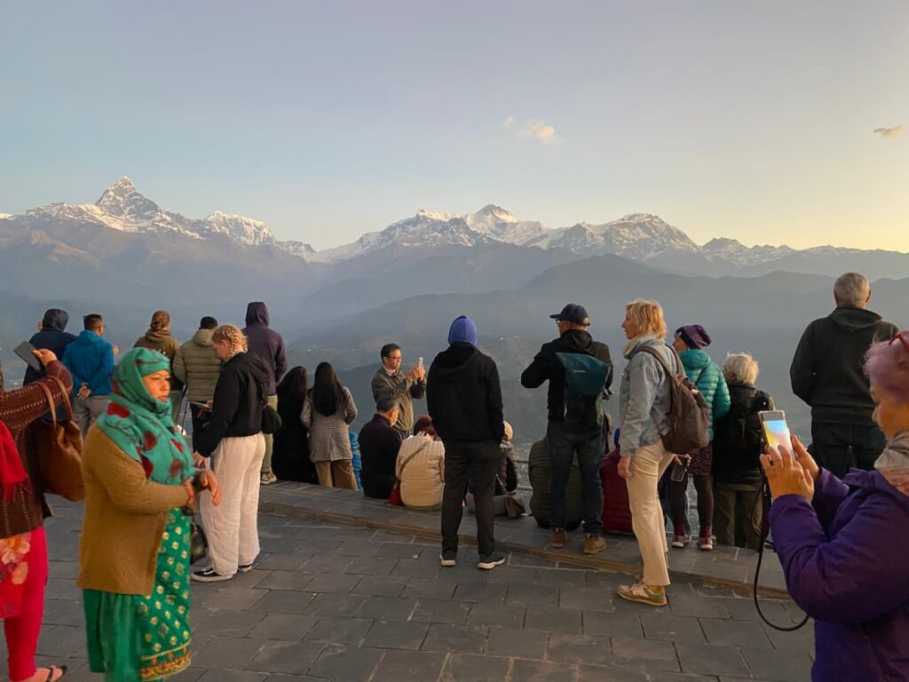 Travellers watching the sunrise over Annapurna and Machhapuchhre mountains from Sarangkot viewpoint on the sightseeing by car tour.