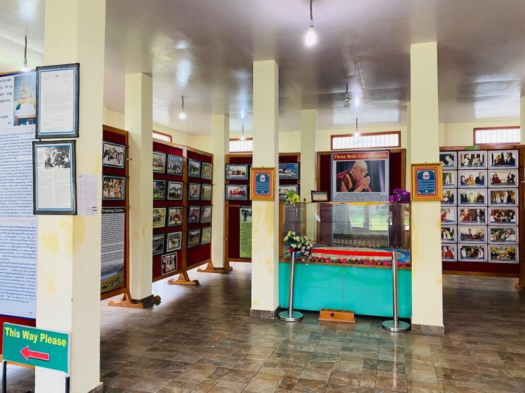Tibetan community photo gallery with historical photographs and sand mandala during a cultural tour in Pokhara