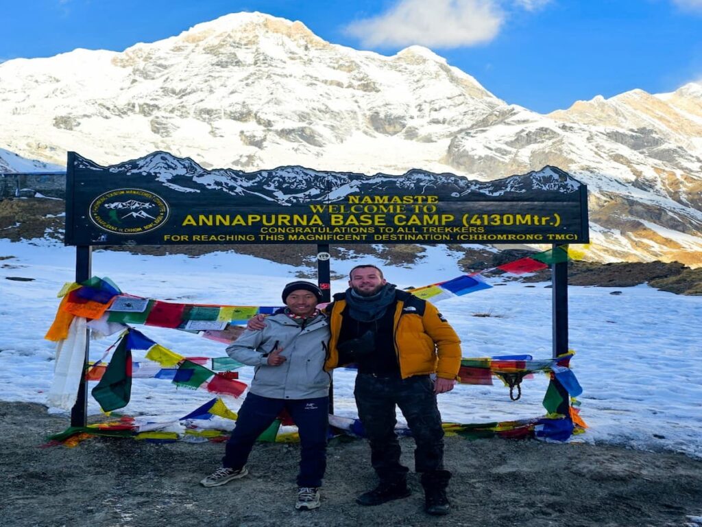 Trekker and guide at the Annapurna Base Camp sign at 4,130m in Nepal