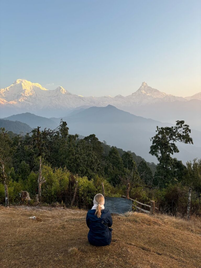 Trekker sitting and watching sunrise over Annapurna and Machhapuchhre from Australian Camp on the Ghandruk Trek 3 Days