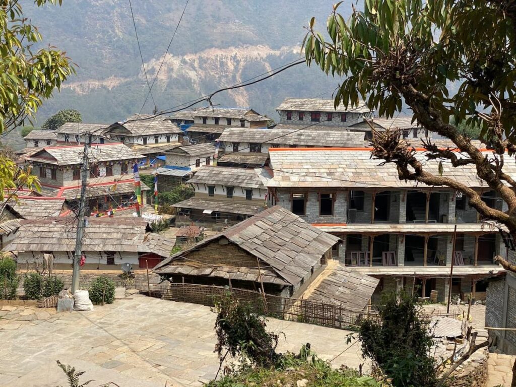 Traditional Gurung stone houses with slate rooftops and prayer flags in a Himalayan mountain village