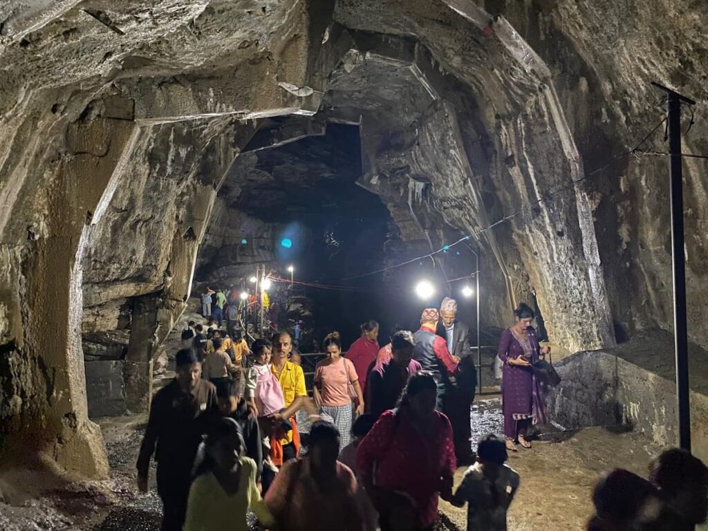 Visitors walking through the illuminated limestone chambers of Gupteshwor Mahadev Cave, one of Nepal's most sacred underground shrines.