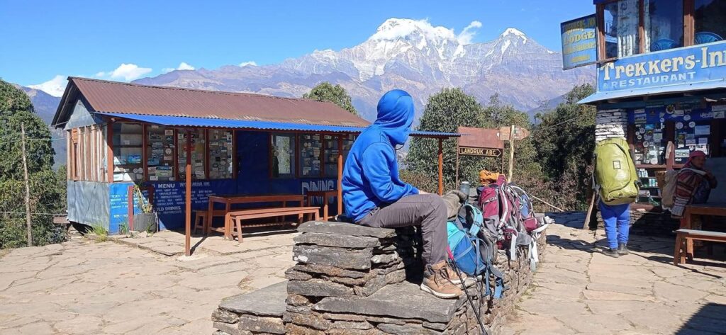 Trekker resting at a mountain lodge on the Australian Camp Trek with Annapurna South behind