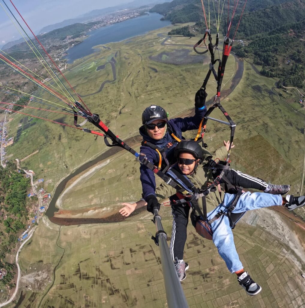 A young guest soaring happily with his instructor above the Pame valley landing zone