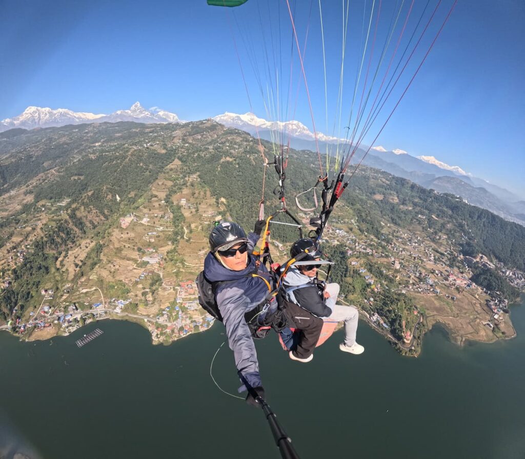 Guided paragliding pilot and guest flying over Machhapuchhre and the Pokhara lakeside