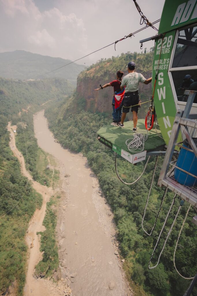 Two guests in harnesses standing on the launch platform before their jump