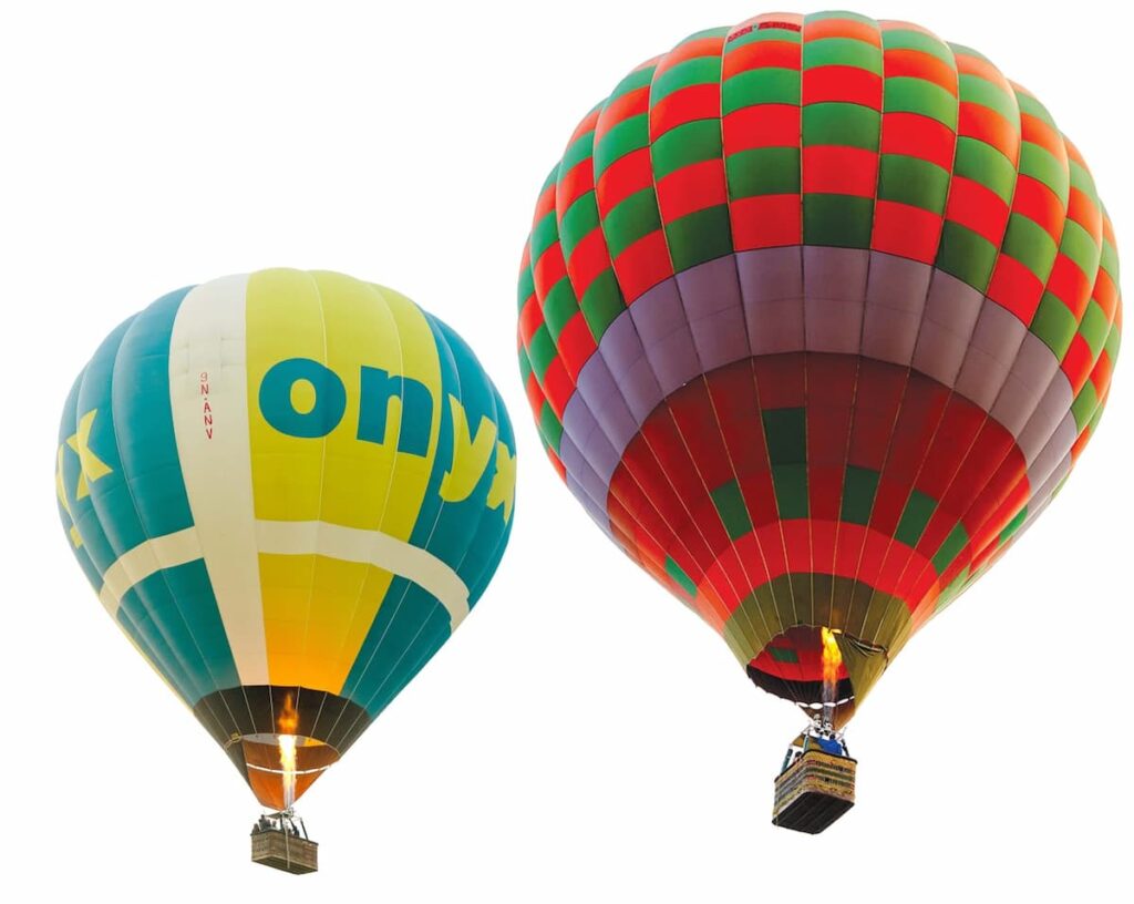 Two colourful balloons flying side by side above the valley
