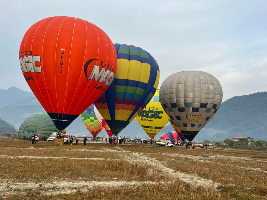 Several colourful balloons inflating together in an open field near Pame Valley