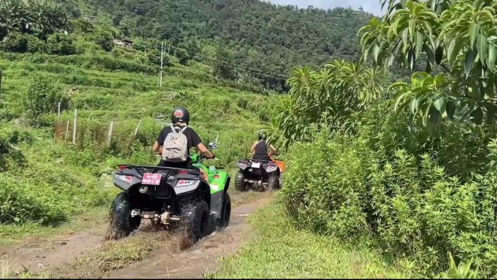 Two riders splashing through a muddy off-road trail