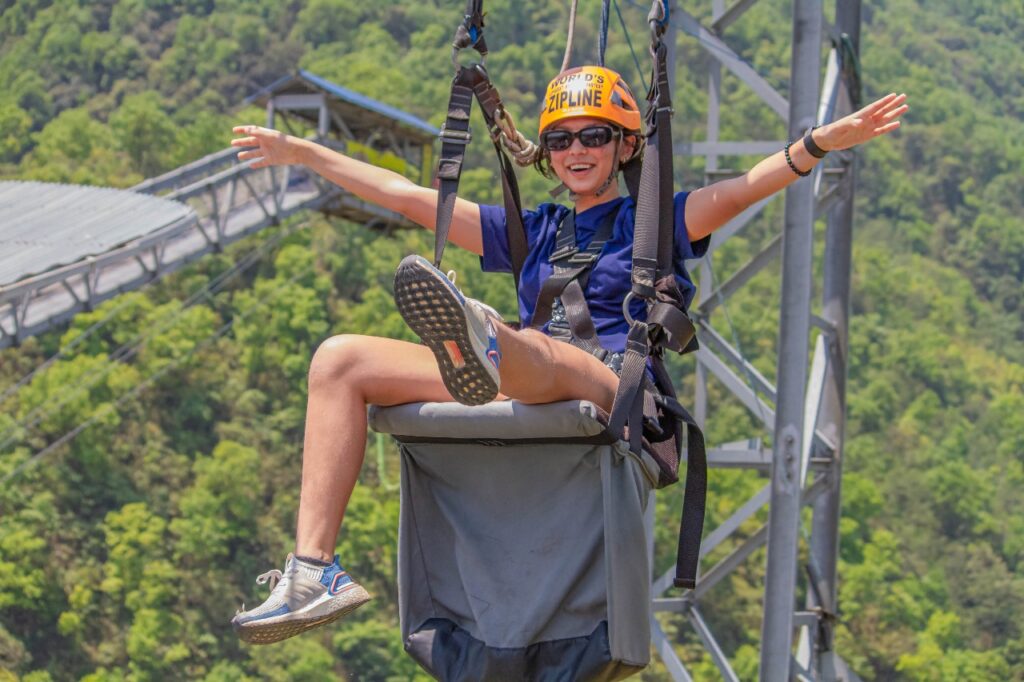 Rider laughing with arms raised mid-flight on the cable