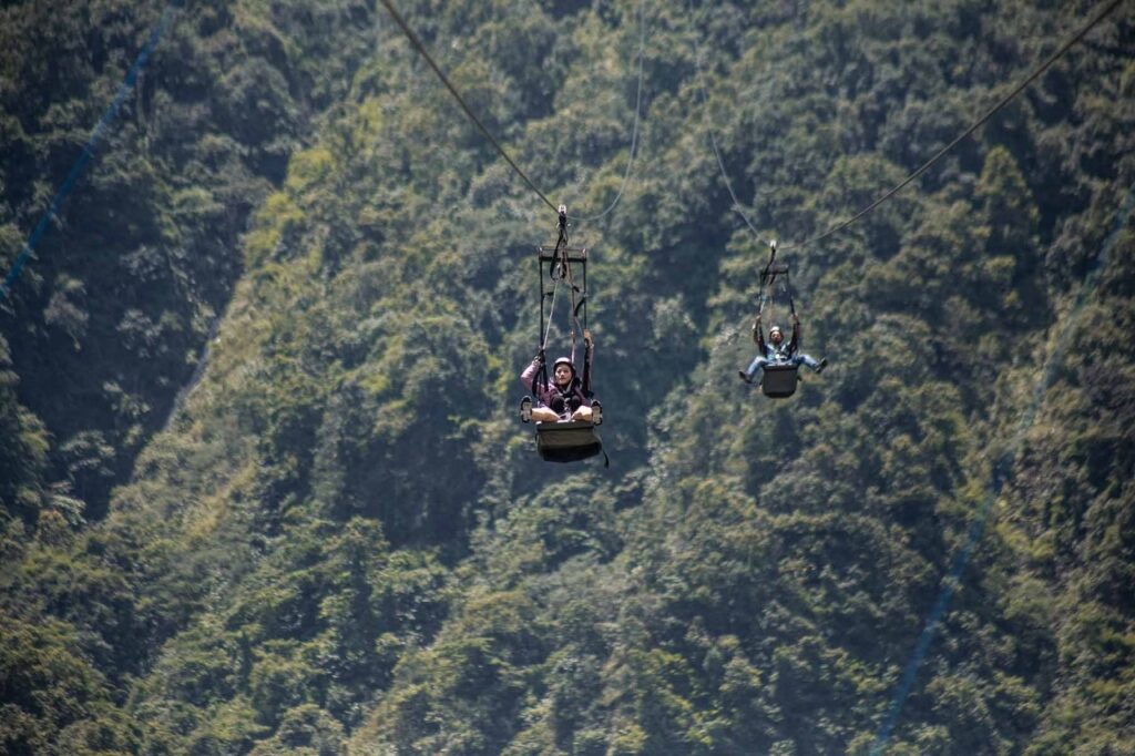 Two riders on the Sarangkot Zipline Pokhara flying over green forest