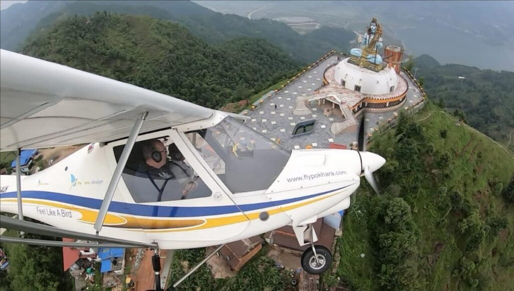 Aircraft passing the Lord Shiva statue above Pokhara on a clear morning